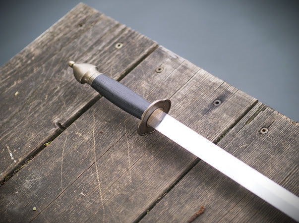 Sword with a black handle on a wooden surface